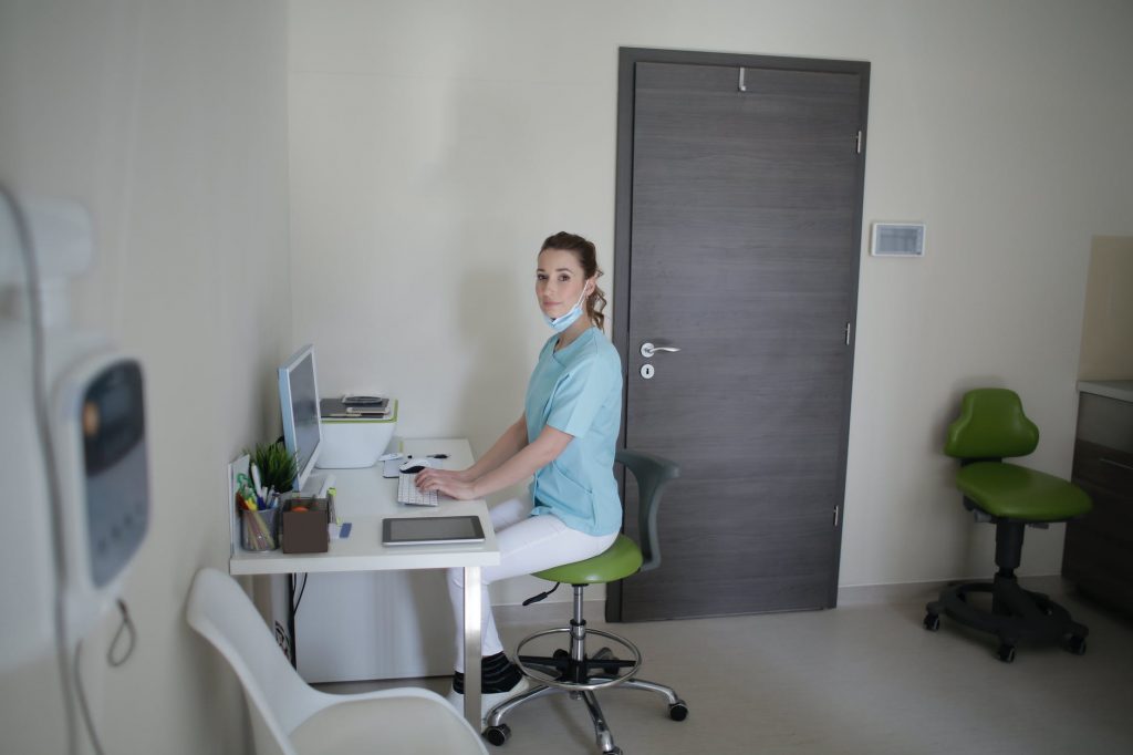 female doctor using desktop computer sitting on chair in clinic